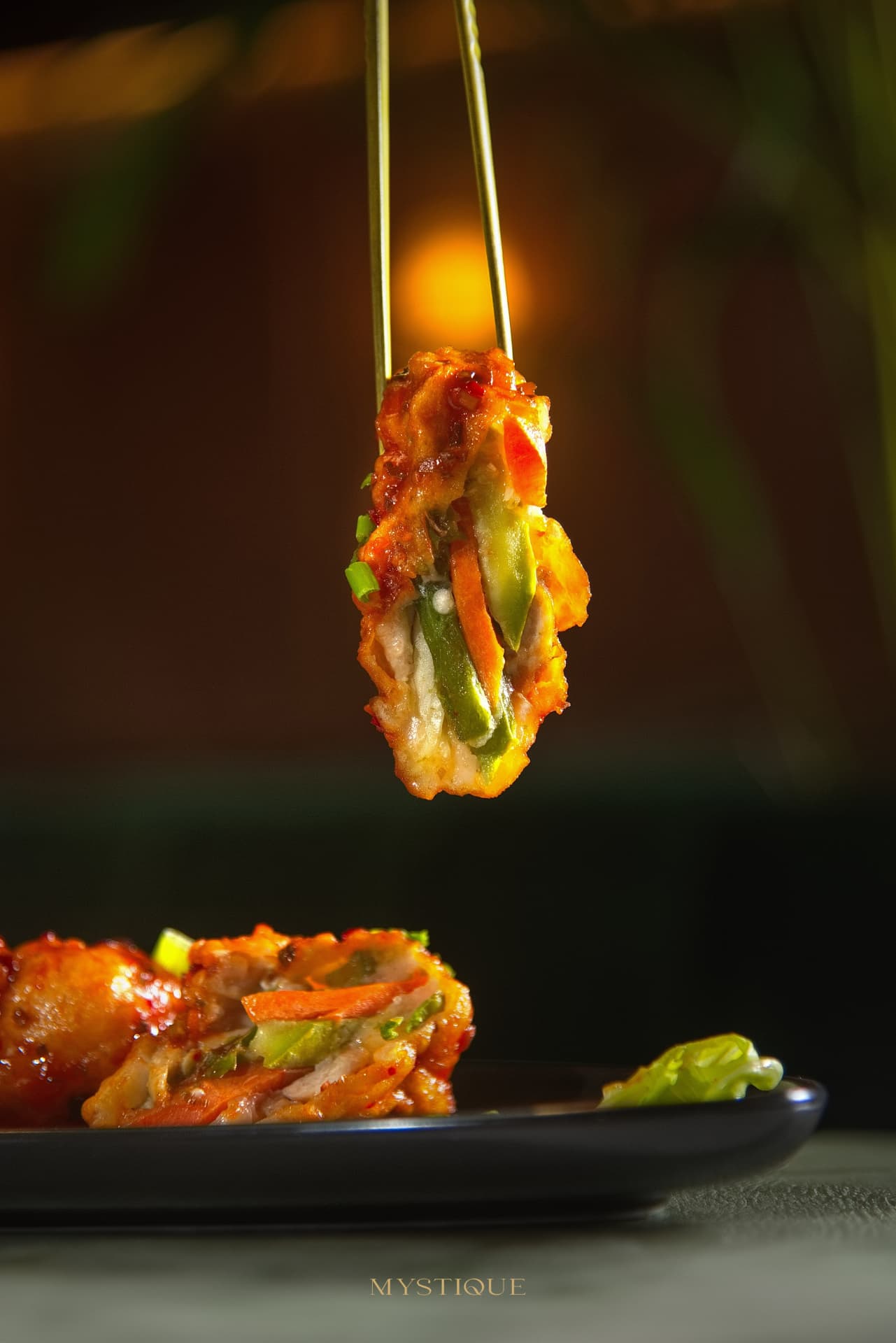 Glazed stuffed chicken roll held with golden chopsticks