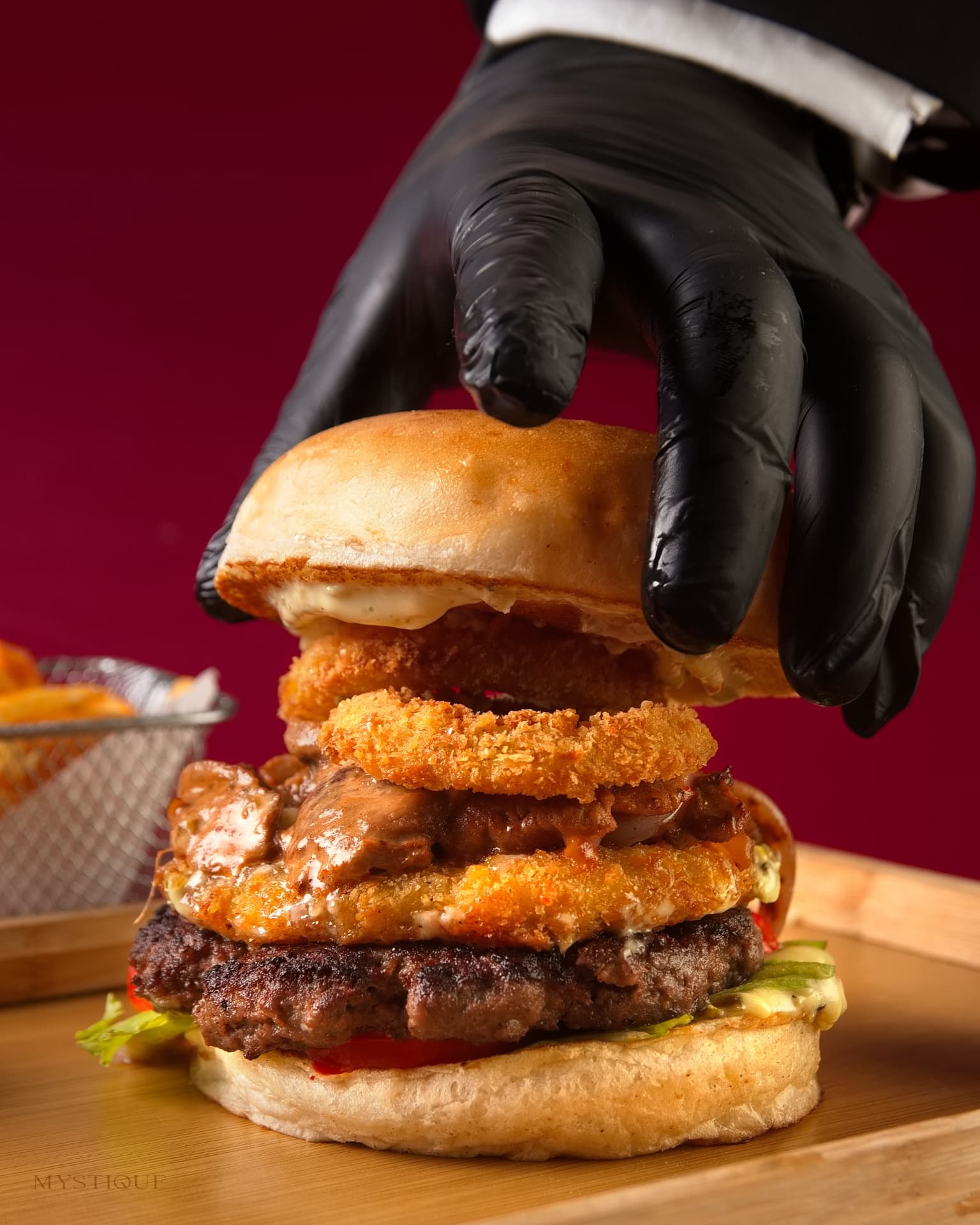 Chef assembling the signature stacked burger with onion rings